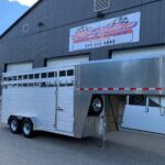 image1 58 - McFarlane Trailer Sales Silver multi-axle gooseneck trailer parked in front of a gray metal building with a large 'MC Haul Trailers Sales' sign above the doors