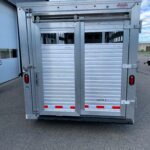 image4 49 - McFarlane Trailer Sales Rear of a silver metal livestock trailer with sliding doors and red reflectors, labeled 'AgHAUL' under a blue sky.