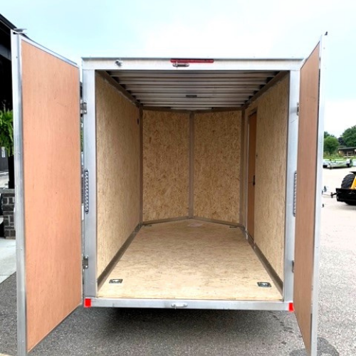 Open back of an empty utility trailer with wooden interior and plywood walls and floor, doors wide open
