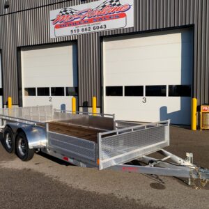 Exterior view of a metal building with three large white garage doors labeled 1, 2, and 3; a silver dual-axle utility trailer in front; yellow bollards and a sign for McLine Trailer Sales above the doors.