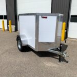 image1 61 - McFarlane Trailer Sales Silver aluminum utility trailer with white sides and diamond-plate front, parked outdoors near a storage building