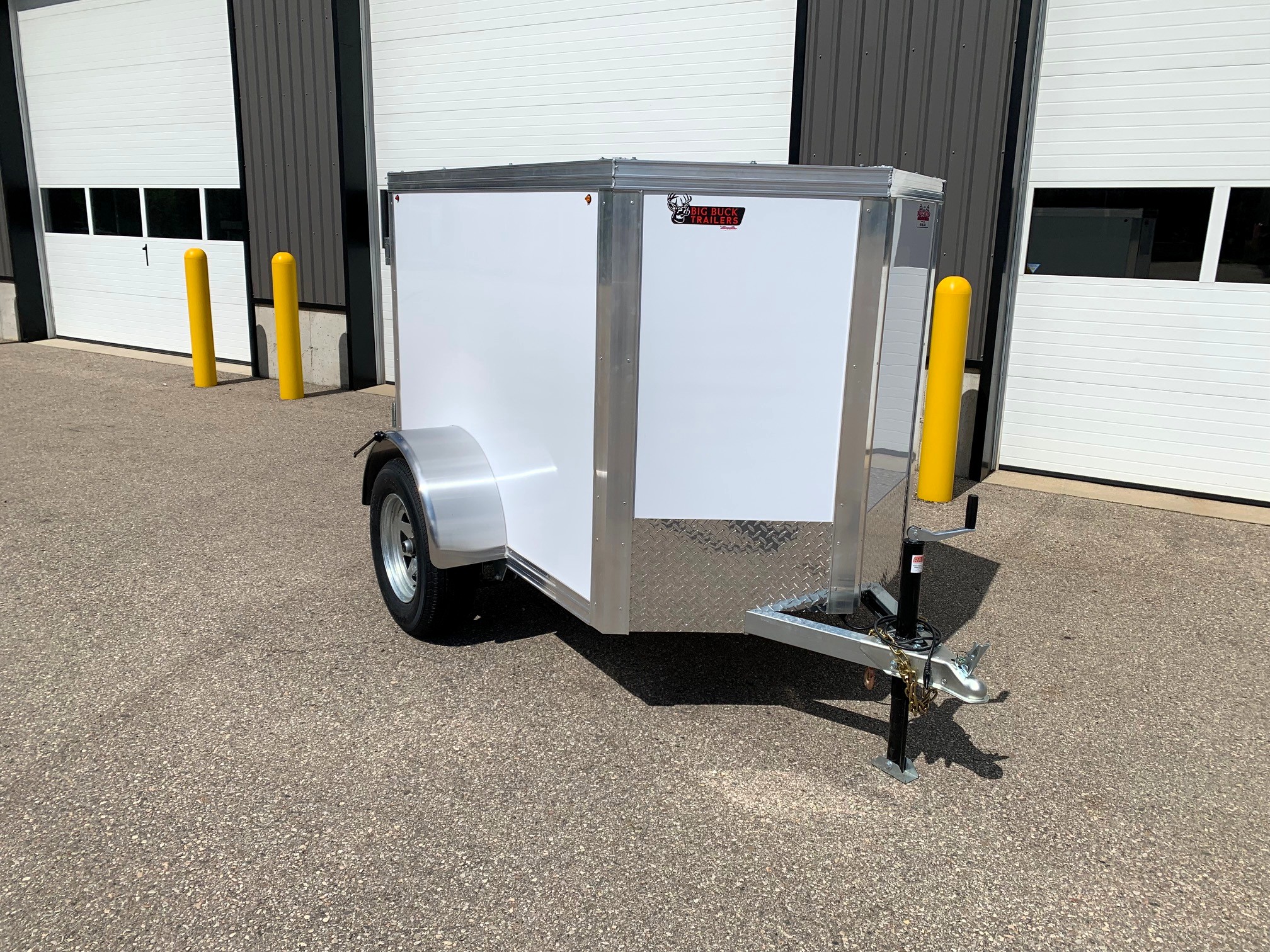 image1 61 - McFarlane Trailer Sales Silver aluminum utility trailer with white sides and diamond-plate front, parked outdoors near a storage building