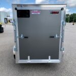 Rear view of a gray cargo trailer with diamond-plate trim and dual latches in a parking lot.