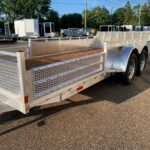 Aluminum utility trailer with diamond-plate sides and wooden deck in a lot, other trailers visible in the background.