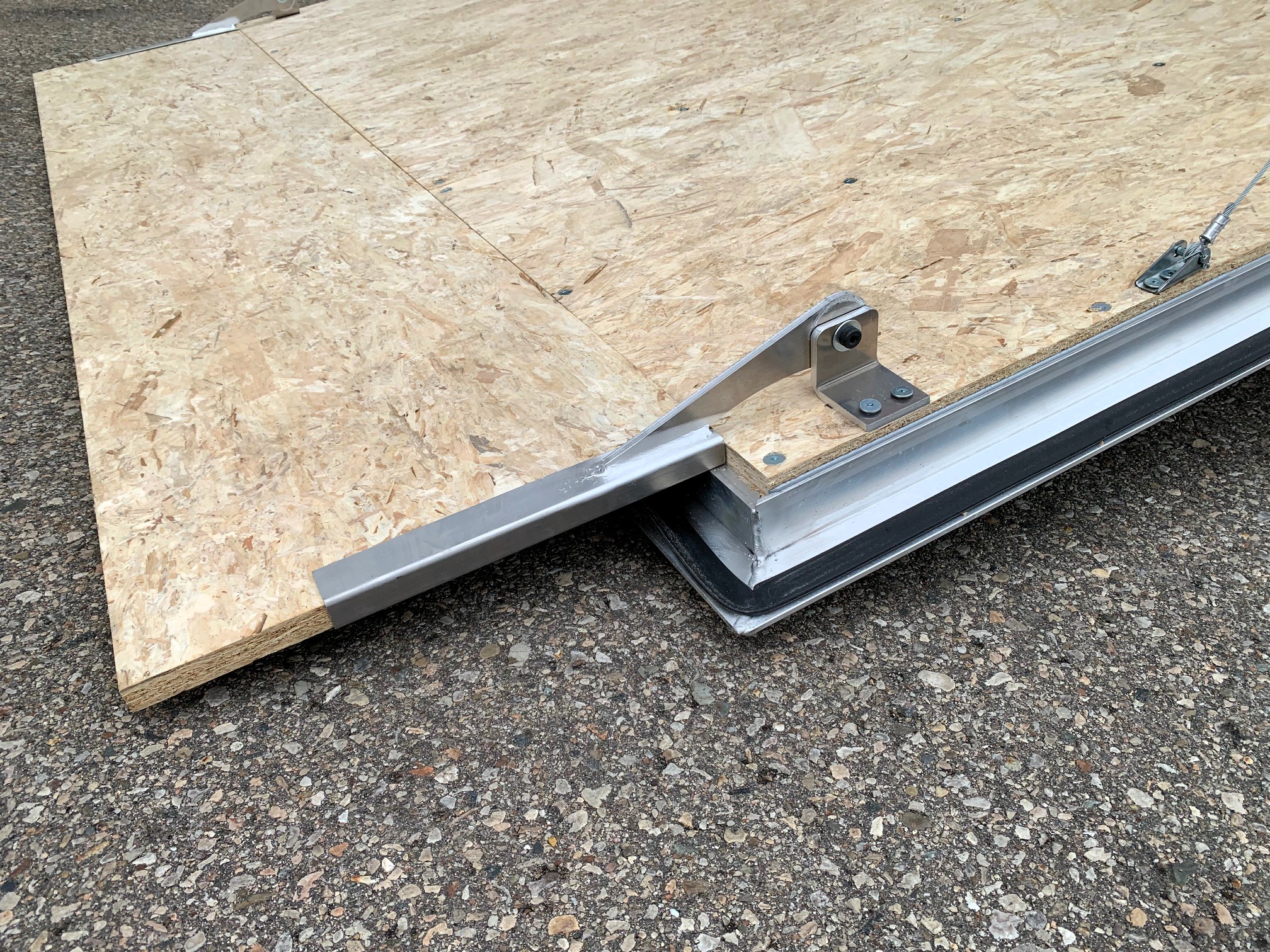 image6 33 - McFarlane Trailer Sales Sheet of OSB plywood resting on a metal trailer bed with support brackets visible at the edge.