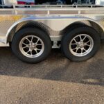 Silver utility trailer with diamond plate sides, dual axles and chrome wheels (tandem tires) photographed outdoors.