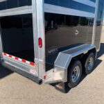 image11 6 - McFarlane Trailer Sales Back view of a shiny aluminum cargo trailer with two rear doors, red taillight, and dual wheels in a parking lot; AgHAUL branding on the bumper tail area.