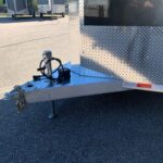 image3 59 - McFarlane Trailer Sales Close-up of a trailer tongue with a hitch, electrical plug and chains on a diamond-plate trailer in a parking lot.