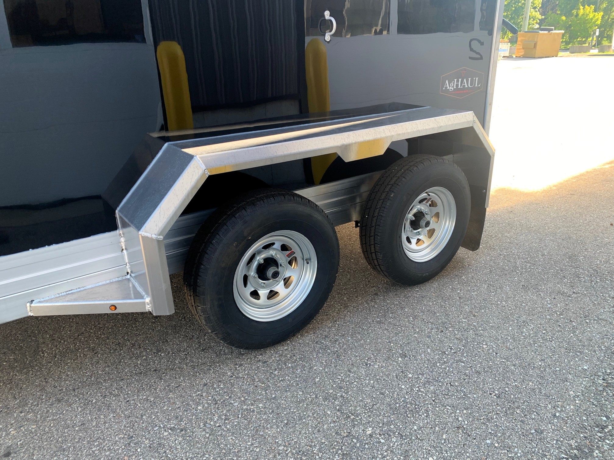 image4 57 - McFarlane Trailer Sales Dual-axle trailer side with diamond-plate fenders, black body, and AgHAUL logo visible.