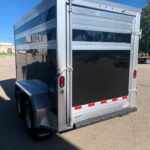 image5 50 - McFarlane Trailer Sales Rear of a silver aluminum cargo trailer with a black back panel, red tail lights, and red-white reflective stripes along the lower edge.