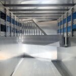 image7 30 - McFarlane Trailer Sales Interior of an empty aluminum trailer with ribbed metal walls and floor, empty cargo area framed by vertical supports.