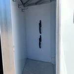image9 8 - McFarlane Trailer Sales Empty metal trailer interior with hooks on the left wall and hanging straps from the ceiling.