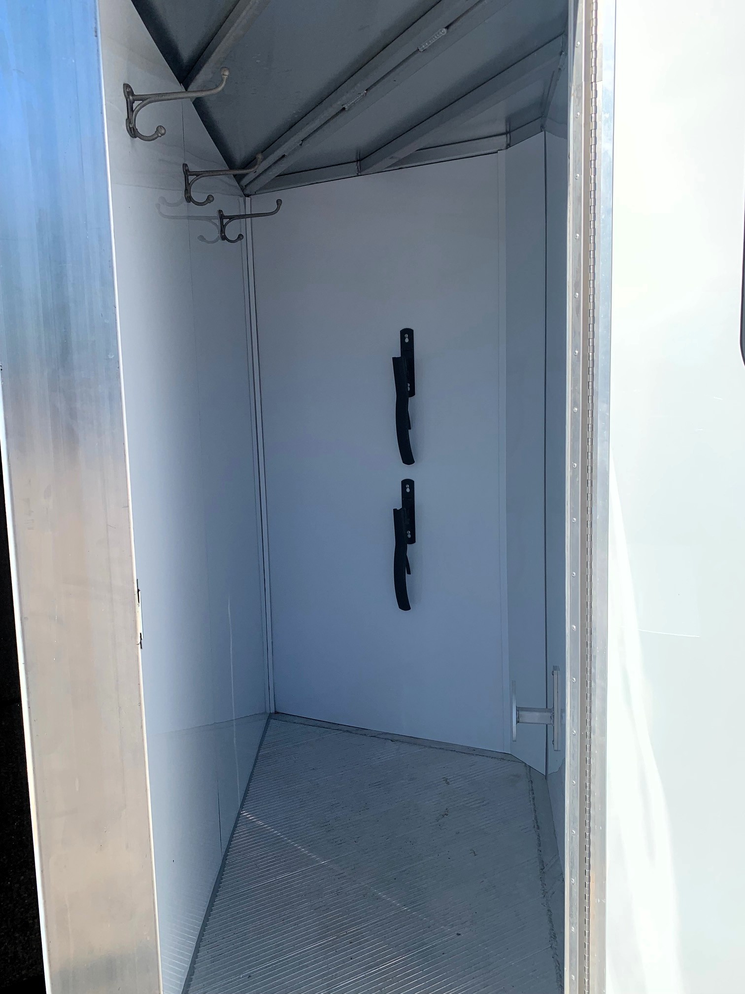 image9 8 - McFarlane Trailer Sales Empty metal trailer interior with hooks on the left wall and hanging straps from the ceiling.