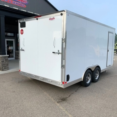 White, two-axle enclosed cargo trailer with rear double doors and diamond-plate trim parked in a lot near a service shop storefront.